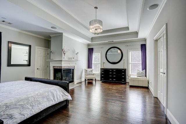 bedroom with wood finished floors, visible vents, an inviting chandelier, a fireplace, and a raised ceiling