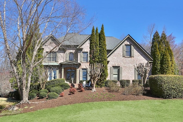 view of front facade with brick siding and a front lawn