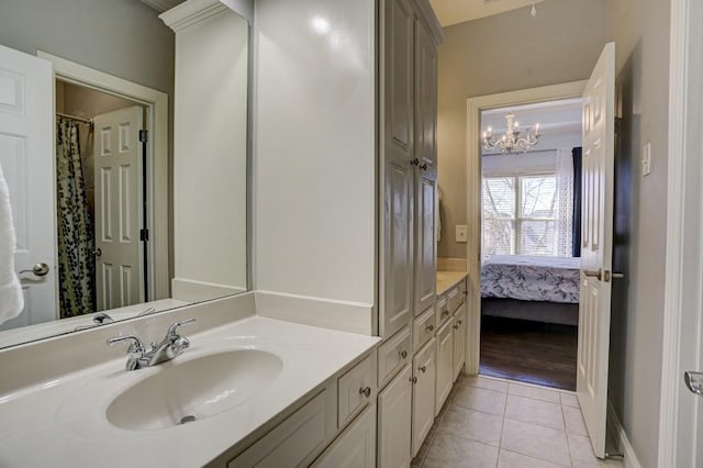 ensuite bathroom featuring tile patterned floors, ensuite bath, an inviting chandelier, baseboards, and vanity