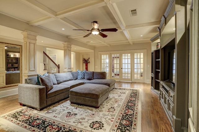 living area with visible vents, a ceiling fan, coffered ceiling, wood finished floors, and decorative columns