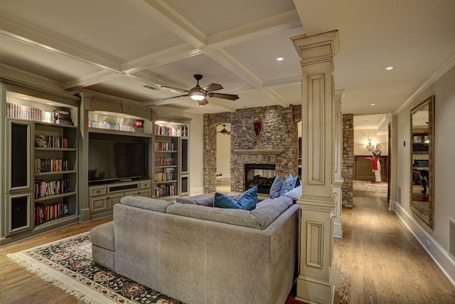 living room featuring coffered ceiling, wood finished floors, a fireplace, and ornate columns