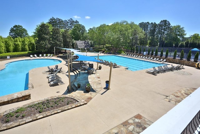 community pool featuring a patio, a water slide, and fence