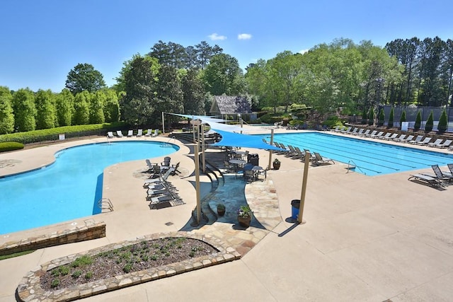 community pool featuring fence, a water slide, and a patio area