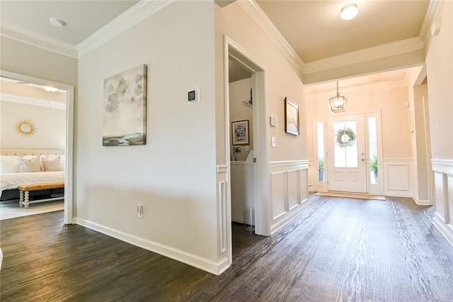 entryway with dark wood-style flooring, crown molding, a decorative wall, and a wainscoted wall