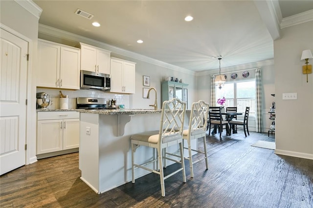 kitchen featuring appliances with stainless steel finishes, ornamental molding, dark wood finished floors, recessed lighting, and light stone countertops