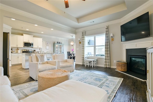 living room featuring a ceiling fan, wood finished floors, recessed lighting, a glass covered fireplace, and crown molding