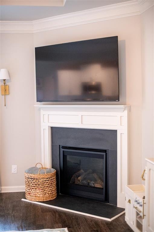 detailed view of a glass covered fireplace, crown molding, and baseboards