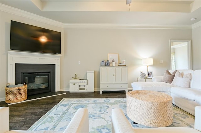 living room with dark wood finished floors, ornamental molding, a glass covered fireplace, and baseboards
