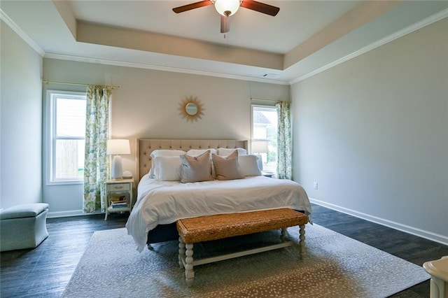 bedroom with a tray ceiling, baseboards, dark wood finished floors, ornamental molding, and ceiling fan