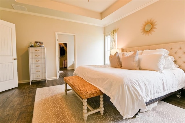 bedroom featuring wood finished floors, baseboards, a spacious closet, and ornamental molding