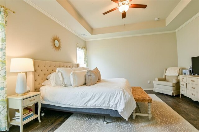 bedroom featuring wood finished floors, a tray ceiling, baseboards, and ceiling fan