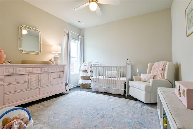 bedroom featuring ceiling fan and a crib