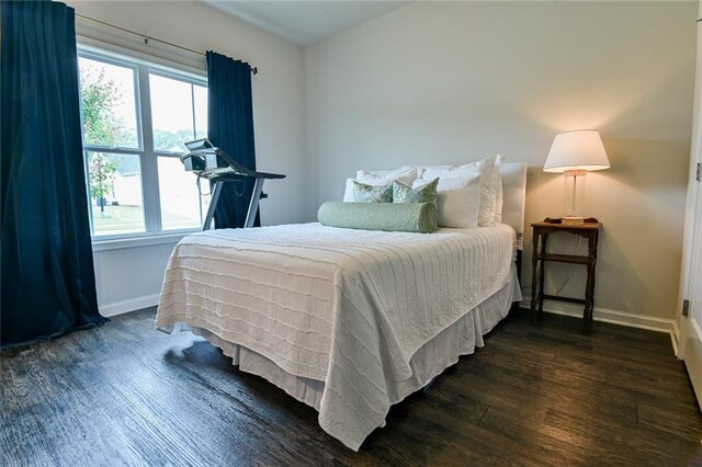 bedroom with dark wood-type flooring and baseboards
