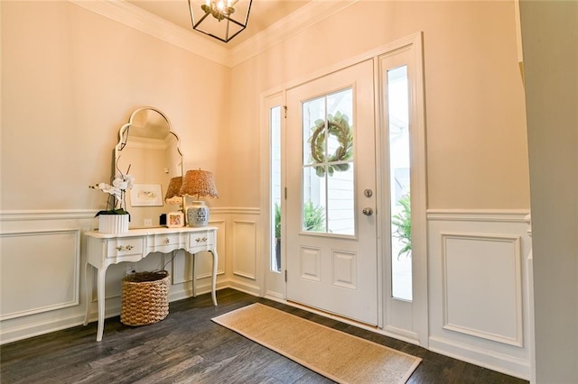 foyer featuring a decorative wall, ornamental molding, wainscoting, dark wood-style flooring, and a chandelier