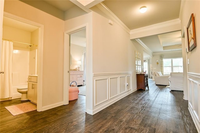 hallway with dark wood-style flooring, crown molding, a decorative wall, and wainscoting