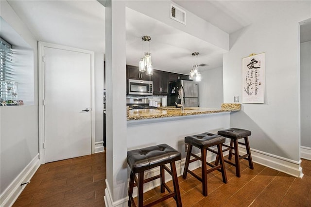 3048 Briarcliff Rd NE Unit 9, Atlanta, GA 30329 - kitchen with appliances with stainless steel finishes, a kitchen breakfast bar, light stone counters, a peninsula, and hanging light fixtures