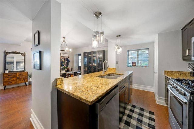 3048 Briarcliff Rd NE Unit 9, Atlanta, GA 30329 - kitchen featuring appliances with stainless steel finishes, dark wood finished floors, light stone countertops, hanging light fixtures, and a center island with sink