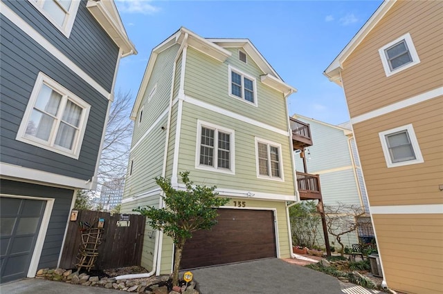 view of front of property with aphalt driveway, a balcony, an attached garage, and fence