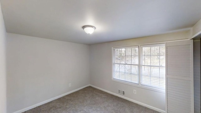 unfurnished room with carpet flooring, visible vents, and baseboards