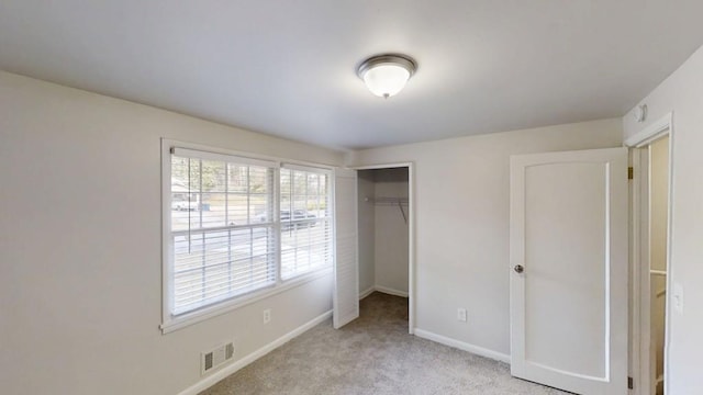 unfurnished bedroom featuring baseboards, a closet, visible vents, and light colored carpet