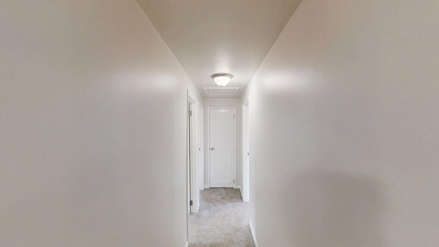 hallway with attic access, carpet, and baseboards