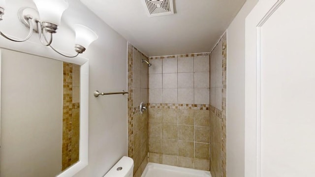 bathroom with visible vents, a tile shower, and toilet