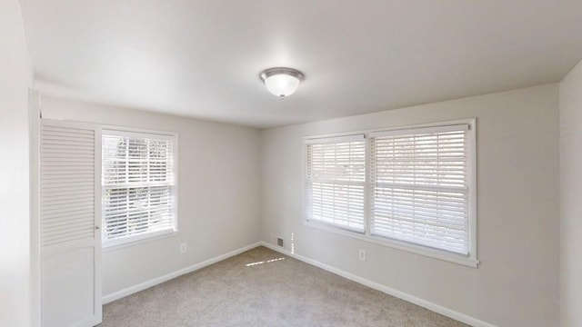 carpeted empty room featuring visible vents and baseboards