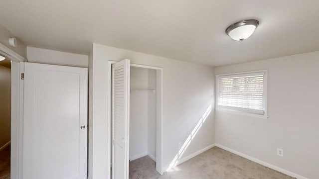 unfurnished bedroom with baseboards, a closet, and light colored carpet