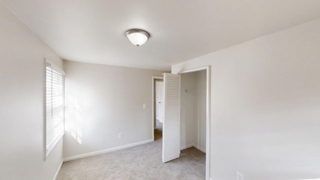 unfurnished bedroom with baseboards, a closet, and light colored carpet