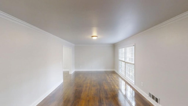 unfurnished room featuring dark wood-style floors, crown molding, visible vents, and baseboards