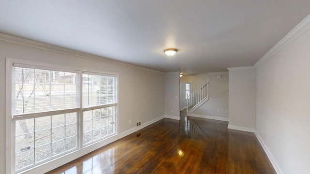 empty room featuring baseboards, stairway, wood finished floors, and ornamental molding