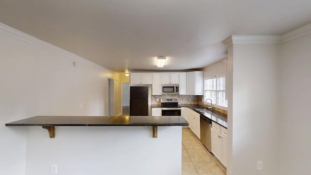 kitchen featuring light tile patterned floors, a peninsula, appliances with stainless steel finishes, and a kitchen bar