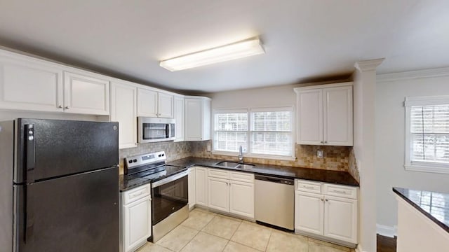 kitchen with stainless steel appliances, decorative backsplash, a sink, and white cabinets