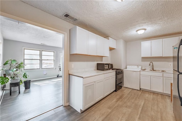 821 Charles Cir, Griffin, GA 30224 - kitchen with gas range oven, light wood-style floors, a textured ceiling, a sink, and light countertops