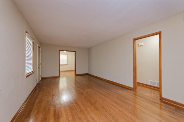 spare room with light wood-type flooring, visible vents, and baseboards