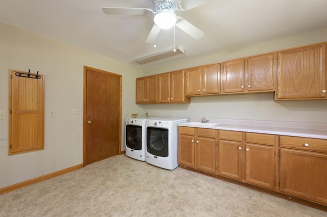 washroom with cabinet space, baseboards, washer and clothes dryer, a ceiling fan, and a sink