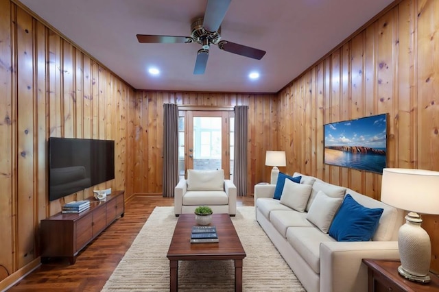 living room featuring wood walls, a ceiling fan, wood finished floors, and recessed lighting