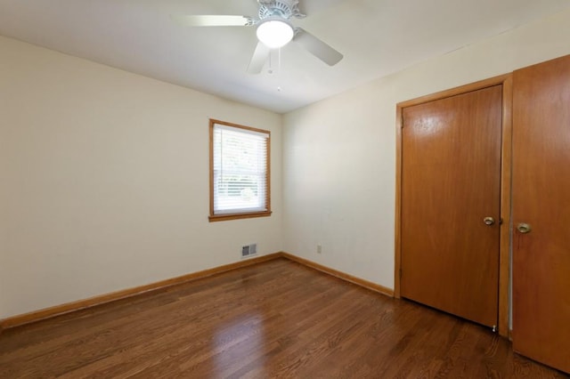 unfurnished bedroom with dark wood finished floors, a closet, visible vents, ceiling fan, and baseboards