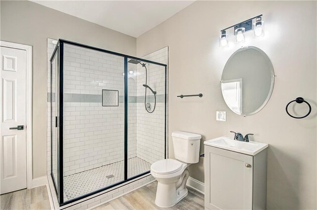 bathroom with vanity, hardwood / wood-style floors, a shower with shower door, and toilet