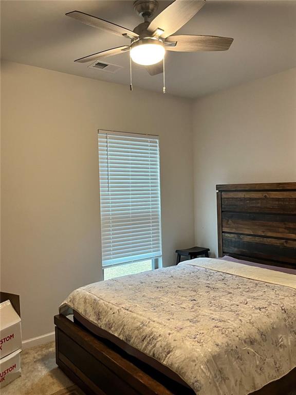 carpeted bedroom featuring ceiling fan, baseboards, and visible vents