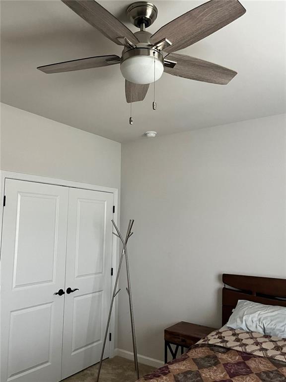 bedroom with a closet, baseboards, and ceiling fan