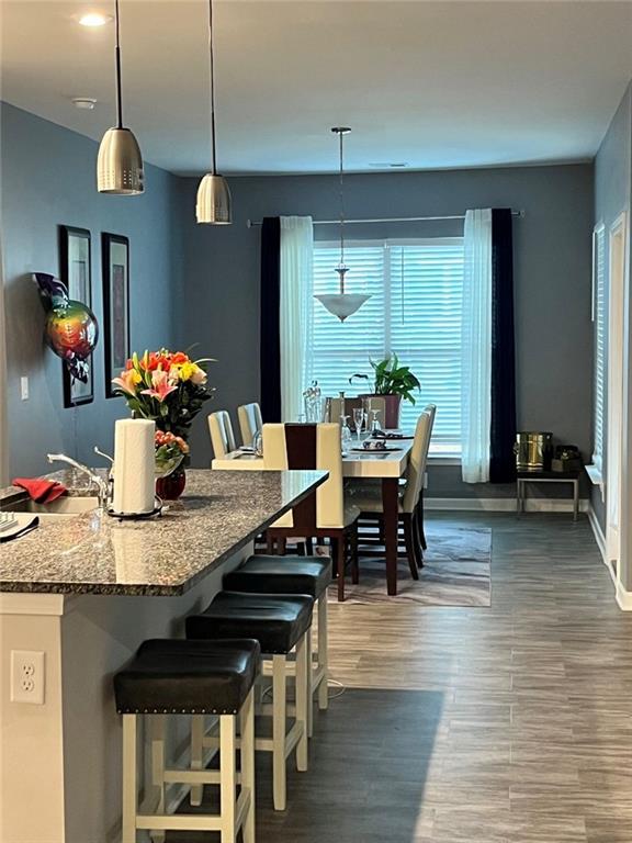 dining room with baseboards, a wealth of natural light, and dark wood-style floors