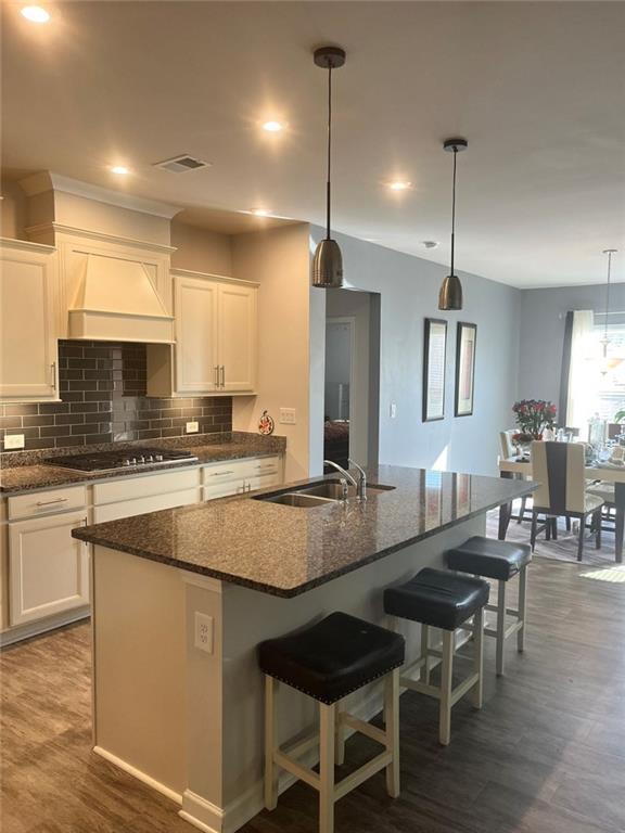 kitchen with white cabinetry, decorative backsplash, custom range hood, and gas cooktop