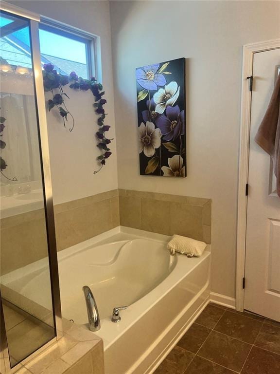 bathroom with walk in shower, tile patterned flooring, baseboards, and a bath