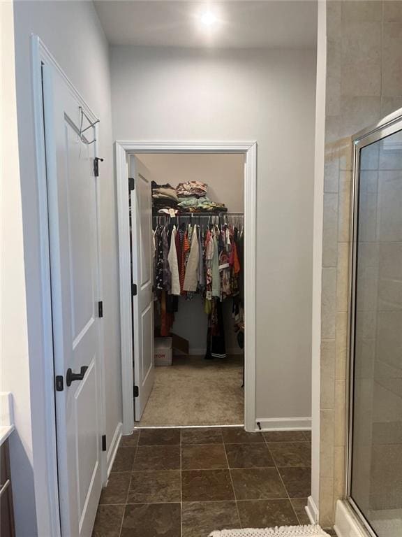 full bath with a shower stall, baseboards, and a walk in closet
