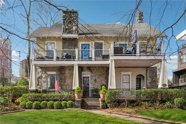 view of front of property featuring a front lawn, a balcony, and a porch