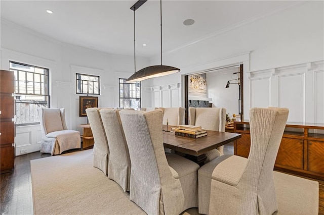 dining area with a decorative wall, recessed lighting, wood finished floors, and ornamental molding