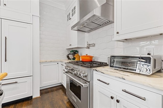 kitchen with stainless steel stove, tasteful backsplash, wall chimney exhaust hood, and white cabinets