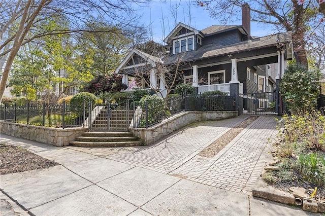 view of front of property with a fenced front yard, a porch, and a chimney