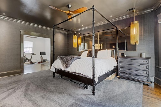 bedroom featuring wood finished floors, visible vents, baseboards, and ornamental molding